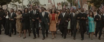 Movie still from “Selma” (2014), directed by Ava DuVernay – A group of people marching down a street holding american flags; Wide shot, High angle