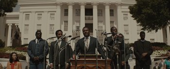 Movie still from “Selma” (2014), directed by Ava DuVernay – A group of men standing around a podium with microphones; Medium shot, Low angle