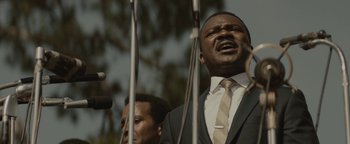 Movie still from “Selma” (2014), directed by Ava DuVernay – A man in a suit and tie holding two microphones; Close Up shot, Low angle