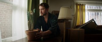 A man sitting at a table with a plant in a pot