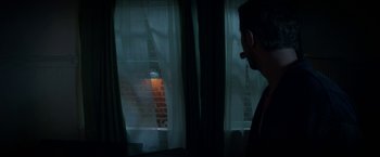 Movie still from “Seven Stages to Achieve Eternal Bliss” (2018), directed by Vivieno Caldinelli – A man smoking a cigarette in front of a window at night; Medium shot, Low angle