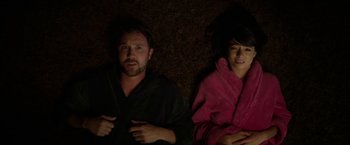 A man and a woman laying on the ground in bathrobes