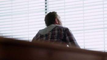 Movie still from “Sharknado” (2013), directed by Anthony C. Ferrante – A man sitting in front of a window with blinds; Medium shot, Low angle