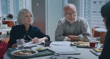 Movie still from “She Said” (2022), directed by Maria Schrader – A man and a woman sitting at a table with plates of food on it; Medium shot, Over the shoulder angle