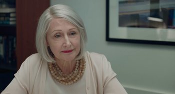 Movie still from “She Said” (2022), directed by Maria Schrader – An older woman wearing a white shirt and a necklace; Close Up shot, Over the shoulder angle