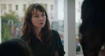 Movie still from “She Said” (2022), directed by Maria Schrader – A woman with long brown hair wearing a black shirt; Close Up shot, Over the shoulder angle