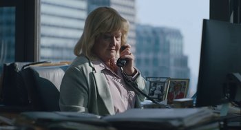 Movie still from “She Said” (2022), directed by Maria Schrader – An older woman talking on a phone while sitting at a desk; Medium shot, Low angle