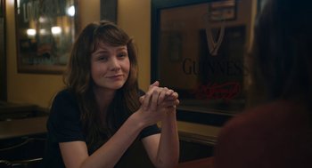 Movie still from “She Said” (2022), directed by Maria Schrader – A woman sitting at a table with her hands clasped together; Close Up shot, Over the shoulder angle