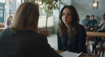Movie still from “She Said” (2022), directed by Maria Schrader – A woman sitting in front of another woman in front of a table; Close Up shot, Over the shoulder angle