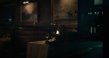Movie still from “She Said” (2022), directed by Maria Schrader – A man sitting at a table with a glass of wine; Wide shot, Over the shoulder angle