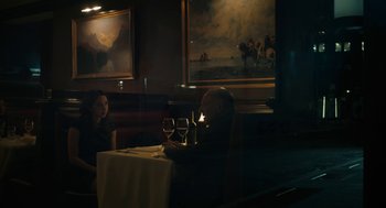 Movie still from “She Said” (2022), directed by Maria Schrader – A man sitting at a table with two glasses of wine; Wide shot, Over the shoulder angle