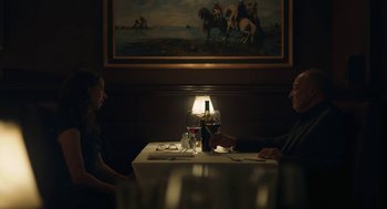 Movie still from “She Said” (2022), directed by Maria Schrader – A man and a woman sitting at a table with a bottle of wine; Medium shot, Over the shoulder angle