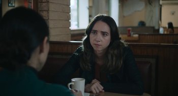 Movie still from “She Said” (2022), directed by Maria Schrader – A woman sitting at a table with a cup of coffee in front of her; Close Up shot, Over the shoulder angle