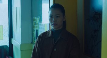 Movie still from “She Said” (2022), directed by Maria Schrader – A woman standing in front of a window in a room; Medium shot, Low angle