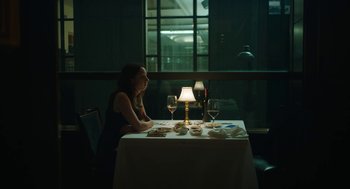 Movie still from “She Said” (2022), directed by Maria Schrader – A woman sitting at a table with a glass of red wine; Wide shot, Over the shoulder angle