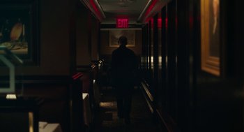 Movie still from “She Said” (2022), directed by Maria Schrader – A man walking down a hallway in a dark room; Wide shot, Low angle