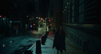 Movie still from “She Said” (2022), directed by Maria Schrader – A woman walking down a sidewalk at night; Extreme Wide shot, High angle