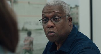 Movie still from “She Said” (2022), directed by Maria Schrader – An older man wearing glasses and a blue shirt; Close Up shot, Over the shoulder angle