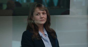 Movie still from “She Said” (2022), directed by Maria Schrader – A woman with long hair wearing a jacket and a white shirt; Close Up shot, Over the shoulder angle