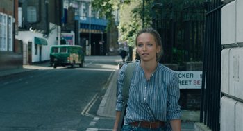 Movie still from “She Said” (2022), directed by Maria Schrader – A woman standing on the side of the street; Medium shot, Over the shoulder angle