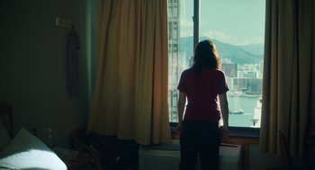 Movie still from “She Said” (2022), directed by Maria Schrader – A woman standing in front of a window looking out; Medium shot, High angle