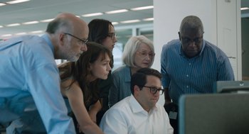 Movie still from “She Said” (2022), directed by Maria Schrader – A group of people looking at a computer screen; Medium shot, High angle