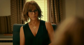 Movie still from “She's Funny That Way” (2014), directed by Peter Bogdanovich – A woman sitting in front of a window wearing glasses; Close Up shot, Over the shoulder angle