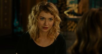 Movie still from “She's Funny That Way” (2014), directed by Peter Bogdanovich – A woman with blonde hair wearing a black shirt; Close Up shot, Over the shoulder angle