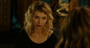 Movie still from “She's Funny That Way” (2014), directed by Peter Bogdanovich – A woman with blonde curly hair looking at the camera; Close Up shot, Over the shoulder angle