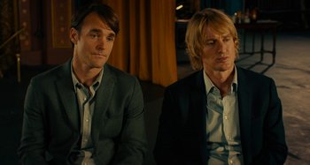 Movie still from “She's Funny That Way” (2014), directed by Peter Bogdanovich – A couple of men sitting next to each other on top of a couch; Medium shot, Over the shoulder angle