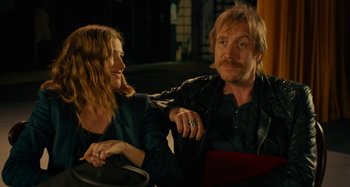 Movie still from “She's Funny That Way” (2014), directed by Peter Bogdanovich – A man and a woman sitting next to each other; Medium shot, Over the shoulder angle
