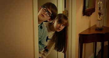 Movie still from “She's Funny That Way” (2014), directed by Peter Bogdanovich – A boy and a girl looking at a mirror; Medium shot, Over the shoulder angle