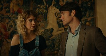 Movie still from “She's Funny That Way” (2014), directed by Peter Bogdanovich – A man and a woman standing next to each other in front of a painting; Medium shot, Over the shoulder angle