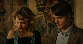Movie still from “She's Funny That Way” (2014), directed by Peter Bogdanovich – A man and a woman standing next to each other in front of a mural; Medium shot, Over the shoulder angle