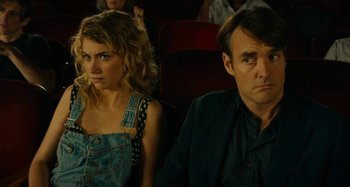 Movie still from “She's Funny That Way” (2014), directed by Peter Bogdanovich – A man and a woman sitting next to each other in a movie theater; Close Up shot, Over the shoulder angle