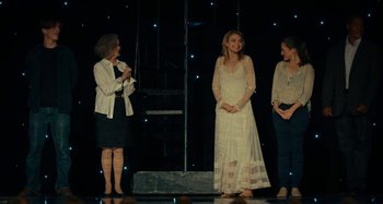 Movie still from “She's Funny That Way” (2014), directed by Peter Bogdanovich – Three women on a stage in front of a black background; Wide shot, Over the shoulder angle