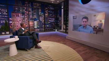Movie still from “Shirley” (2020), directed by Josephine Decker – A man sitting in a chair in front of a television; Wide shot, Over the shoulder angle