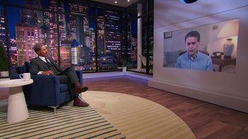 Movie still from “Shirley” (2020), directed by Josephine Decker – A man sitting on a blue chair in front of a tv; Wide shot, Over the shoulder angle