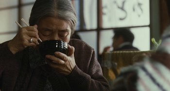 Movie still from “Shoplifters” (2018), directed by Kore-eda Hirokazu – An older woman is drinking a cup of coffee; Close Up shot, Over the shoulder angle