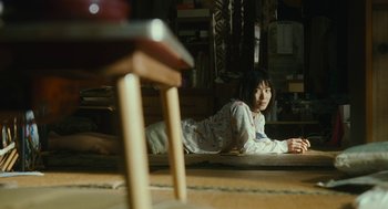 Movie still from “Shoplifters” (2018), directed by Kore-eda Hirokazu – A woman laying on the ground in a room; Wide shot, High angle