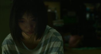 Movie still from “Shoplifters” (2018), directed by Kore-eda Hirokazu – A woman sitting in a dark room looking down at the floor; Close Up shot, Low angle