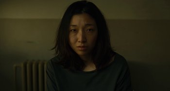 Movie still from “Shoplifters” (2018), directed by Kore-eda Hirokazu – A woman with long black hair sitting in a dark room; Close Up shot, High angle