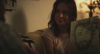Movie still from “Short Term 12” (2013), directed by Destin Daniel Cretton – A woman sitting on a couch looking at the camera; Close Up shot, Over the shoulder angle