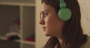Movie still from “Short Term 12” (2013), directed by Destin Daniel Cretton – A woman wearing a green headphones looking to the side; Close Up shot, Over the shoulder angle