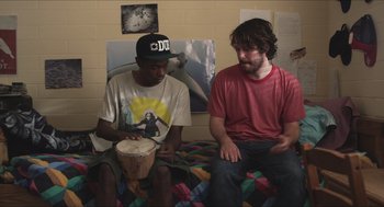 Movie still from “Short Term 12” (2013), directed by Destin Daniel Cretton – Two men sitting on a bed and one of the men is playing a drum; Medium shot, Over the shoulder angle