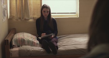 Movie still from “Short Term 12” (2013), directed by Destin Daniel Cretton – A girl sitting on a bed writing in a notebook; Medium shot, High angle