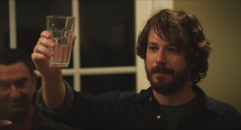 Movie still from “Short Term 12” (2013), directed by Destin Daniel Cretton – A man holding up a glass of water in his right hand; Close Up shot, Over the shoulder angle