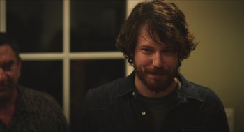 Movie still from “Short Term 12” (2013), directed by Destin Daniel Cretton – A man with long hair and a beard smiling for the camera; Close Up shot, Over the shoulder angle