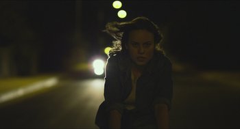 Movie still from “Short Term 12” (2013), directed by Destin Daniel Cretton – A woman sitting on the side of a road at night; Medium shot, Over the shoulder angle