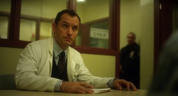 Movie still from “Side Effects” (2013), directed by Steven Soderbergh – A man sitting at a table in front of a window; Medium shot, Low angle